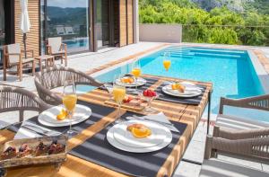 - une table avec de la nourriture et des boissons à côté de la piscine dans l'établissement Palazzo Vimbula - Five Star Luxury Villa, à Mokošica