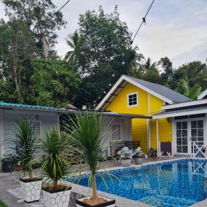 uma casa amarela com uma piscina em frente em Cheqma Tiny Chalet em Kota Bharu