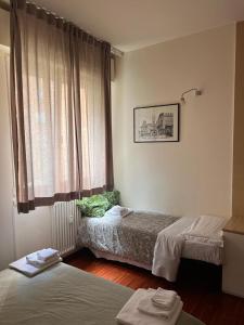 ボローニャにあるScendi dal trenoのベッドルーム1室(ベッド2台付)、窓(カーテン付)