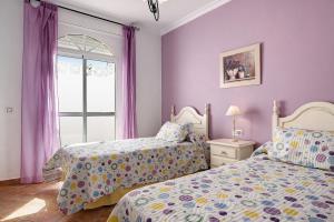 two beds in a bedroom with purple walls and a window at Chalet Fuente3 piscina común famila in Conil de la Frontera +16 photos