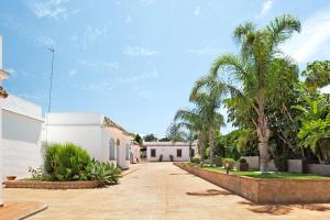a driveway leading to a white building with palm trees at Chalet Fuente3 piscina común famila in Conil de la Frontera