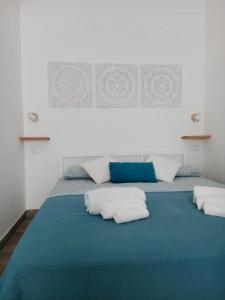 a blue bed with three pillows on top of it at Camere A Oriente II in Torre dell'Orso