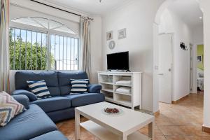 a living room with a blue couch and a tv at Chalet Fuente3 piscina común famila in Conil de la Frontera