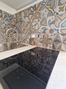 a kitchen with a sink and a tile wall at Camere A Oriente II in Torre dell'Orso