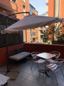 a table and chairs and an umbrella on a balcony at Scendi dal treno in Bologna