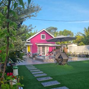 ein Haus mit einem roten Haus und einem Rasen in der Unterkunft Cheqma Tiny Chalet in Kota Bharu