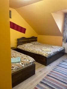 Duas camas num quarto com paredes amarelas em Pensiunea Iza em Bradu