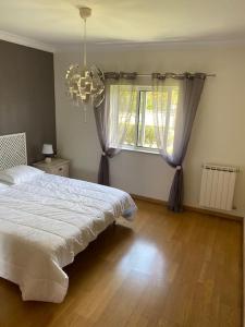 a bedroom with a white bed and a window at Villa avec piscine dans un golf in Palmela