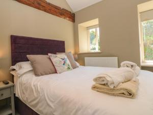um quarto com uma cama com lençóis brancos e almofadas em The Old Dairy em Thirsk