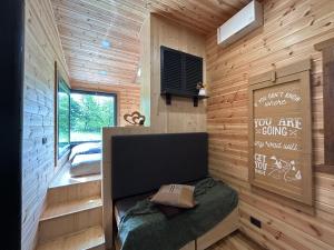 a small room with a bed in a wooden wall at Cãsuța de sub nuc in Piatra Neamţ