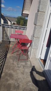 a red table and chairs sitting on a balcony at Au rayon de soleil in Trédias