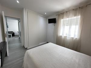 een witte slaapkamer met een bed en een raam bij Casa na Vila by Trip2Portugal in Figueiró dos Vinhos