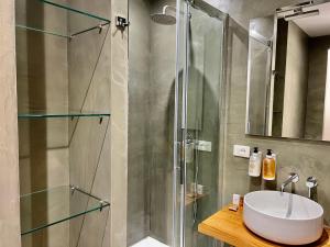 uma casa de banho com uma cabina de duche em vidro e um lavatório. em La Vaticana em Roma