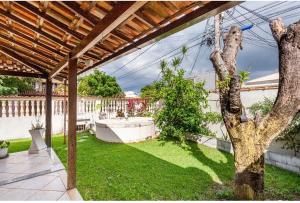 a backyard with a tree and a wooden pergola at Casa aconchegante à 200m da praia in Rio das Ostras