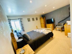 ein Schlafzimmer mit einem Bett, einem Stuhl und einem TV in der Unterkunft The Maltsters Country Inn in Badby