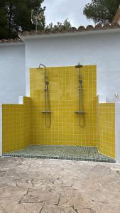 una pared de baldosas amarillas con dos duchas. en Villa Shangri La Family, en Colonia de San Pedro