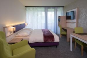 a hotel room with a bed and a desk and a television at wohnMOTEL - Hinterforst in Altstätten