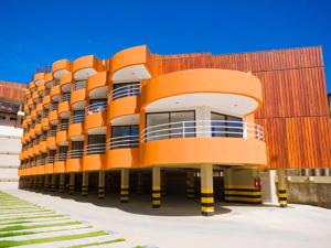 un gran edificio de color naranja con balcones en un lateral. en Marsallis Praia Mar, en Natal