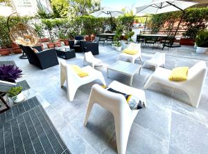 een patio met witte stoelen, tafels en parasols bij Hotel Franchi in Florence