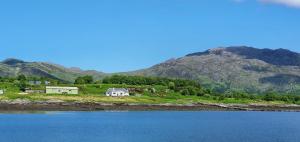 AcharacleにあるIsle of Carna, secluded Scottish Island, Loch Sunartの水の横の丘の上の家