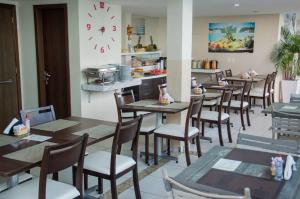 un restaurante con mesas y sillas de madera y un reloj en Marsallis Praia Mar, en Natal
