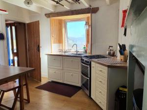 a kitchen with a stove and a sink and a window at Isle of Carna, secluded Scottish Island, Loch Sunart in Acharacle