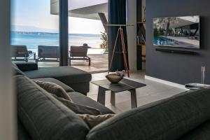 a living room with a couch and a table with a tv at Villa Trinity - Hillside villa with Sea View and Infinity Pool in Kali