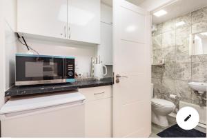 a white kitchen with a microwave and a toilet at En-suite room in central Milton Keynes in Milton Keynes