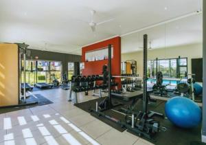 einen Fitnessraum mit vielen Geräten und einem Pool in der Unterkunft The Henlee Apartment on Ventura in Sandton