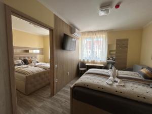 a hotel room with two beds and a television at Harmony Apartments in Eger