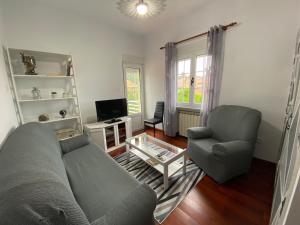 un soggiorno con divano, sedia e TV di Casa Elsa a Torrelavega