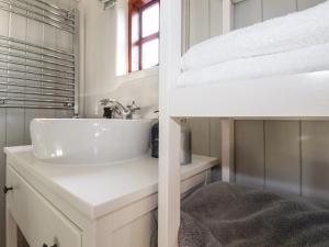 a white bathroom with a sink and a mirror at Puddle Duck Shepherds Hut in Launceston