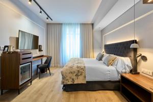 a bedroom with a bed and a desk and a television at Catalonia El Pilar in Zaragoza