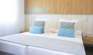 a large white bed with blue pillows on it at Labranda Alyssa Suite Hotel in Playa Blanca