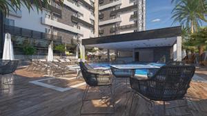 a patio with chairs and a table and a swimming pool at SPAZZIO DiROMA HOTEL COM ACESSO AO ACQUA PARK in Caldas Novas