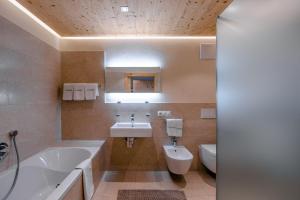 La salle de bains est pourvue d'une baignoire, d'un lavabo et de toilettes. dans l'établissement Ciasa Agreiter, à La Villa