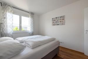 two beds in a white room with a window at Grüne Ruhelage, 20 Minuten ins Zentrum und Parkgarage in Vienna