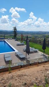 a swimming pool with umbrellas and chairs next to at Quinta da Pedrulha in Valhelhas