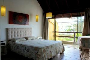 a bedroom with a bed and a large window at Pousada Bangalôs Da Mole - Florianópolis in Florianópolis