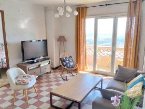 un soggiorno con TV, divano e sedie di Appartement lumineux quartier calme a Grasse