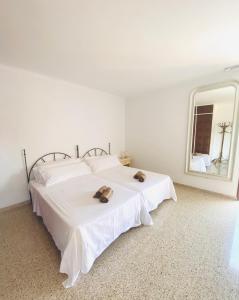 a white bedroom with a large white bed and a mirror at Villa urbana con Piscina en Playa den Bossa in Ibiza Town