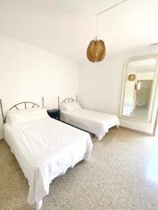 a white room with two beds and a mirror at Villa urbana con Piscina en Playa den Bossa in Ibiza Town