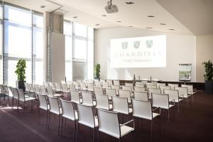 a room with a row of chairs and a screen at UNAHOTELS Malpensa in Cerro Maggiore