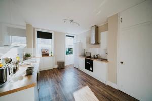 cocina con armarios blancos y suelo de madera en Roman Penthouse- Skyline Views, 4K TVs, Offsite Parking, 5G WIFI and more!, en Bath