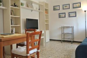 Zimmer mit einem Schreibtisch, einem TV sowie einem Tisch und Stühlen. in der Unterkunft Casa Lino in Volterra