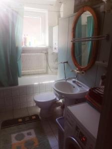a bathroom with a sink and a toilet and a mirror at Przytulny dom z ogrodem i tarasem in Koszalin