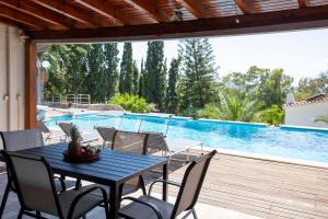 a table and chairs on a patio with a swimming pool at Green Villa Aegina in Aegenitissa