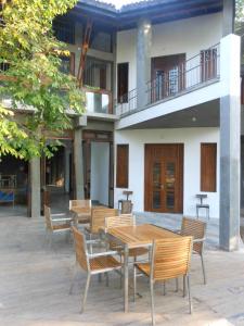 eine Terrasse mit Holztischen und -stühlen vor einem Gebäude in der Unterkunft Isana Beach House in Tangalle