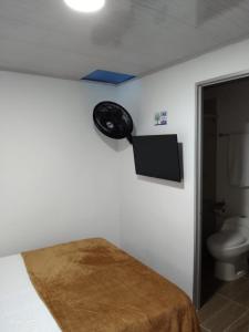 a bathroom with a toilet and a television on the wall at Hotel Brisas Del Rio SH in Tuluá