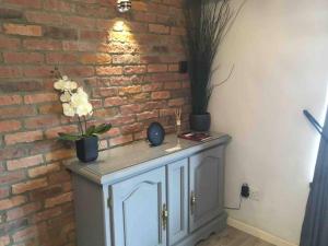 a white cabinet with flowers on it next to a brick wall at Y Bwythyn - Lovely cottage in village of Spittal in Haverfordwest